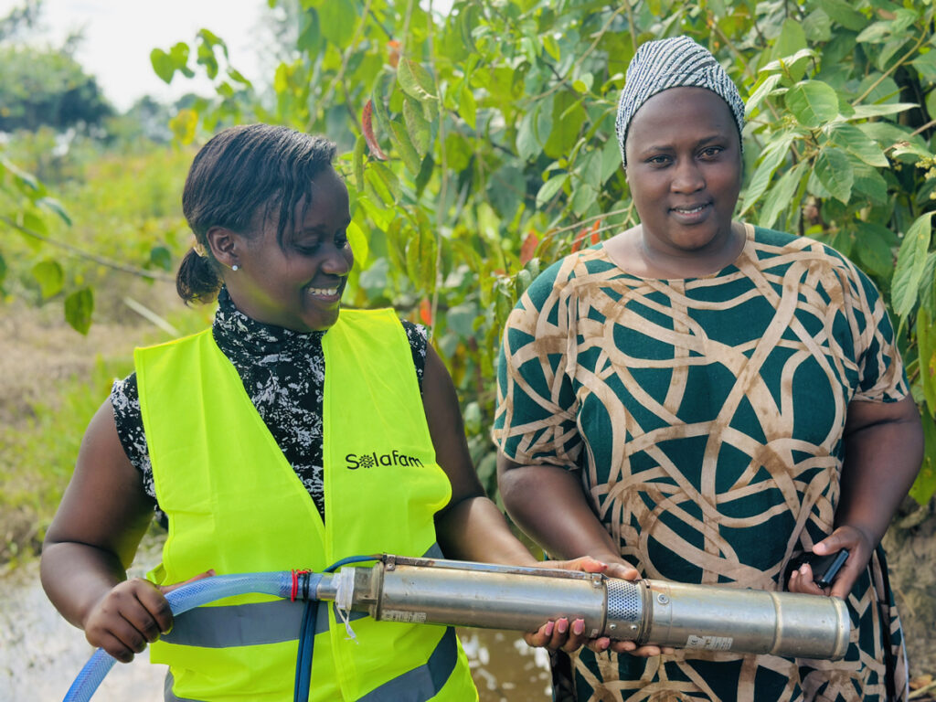 Shifra Ainomugisha und eine Landwirtin mit einer solarbetriebenen Bewässerungspumpe in Uganda.